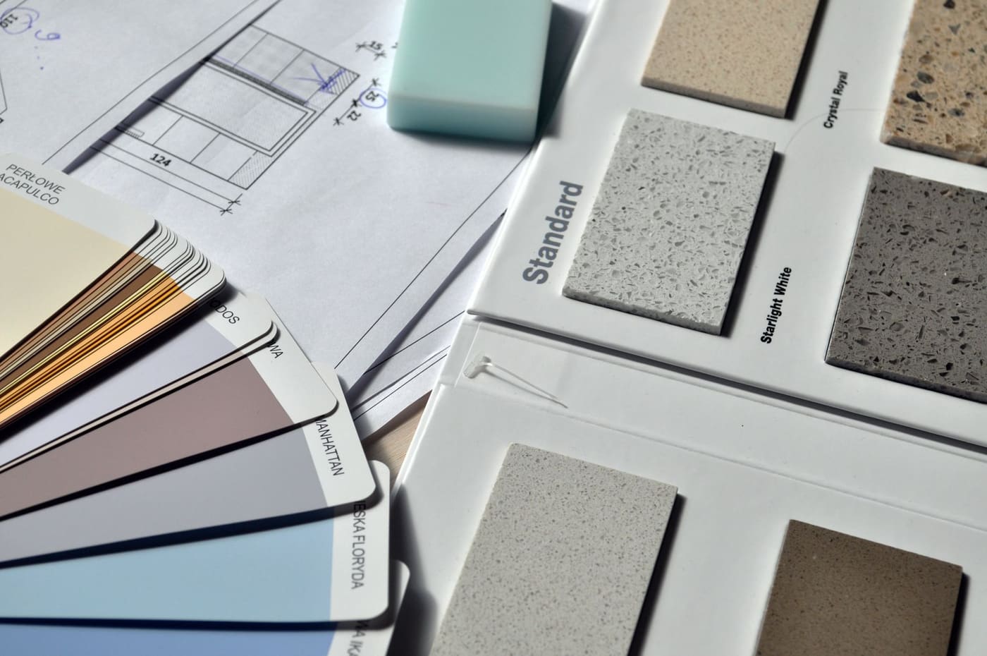 Paint color fans and stone material samples spread over a printed floor plan