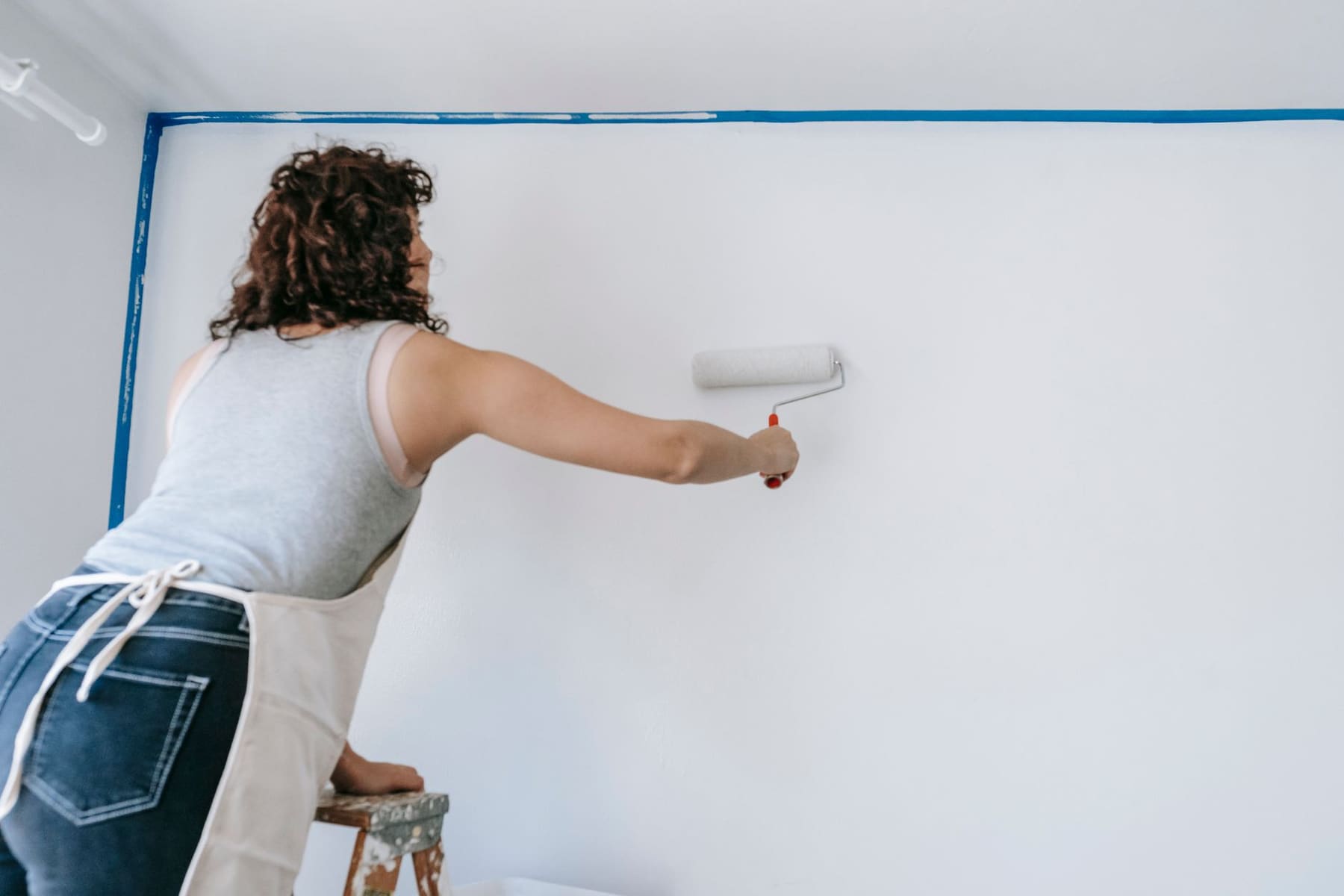 A roller painting a wall in a bright room