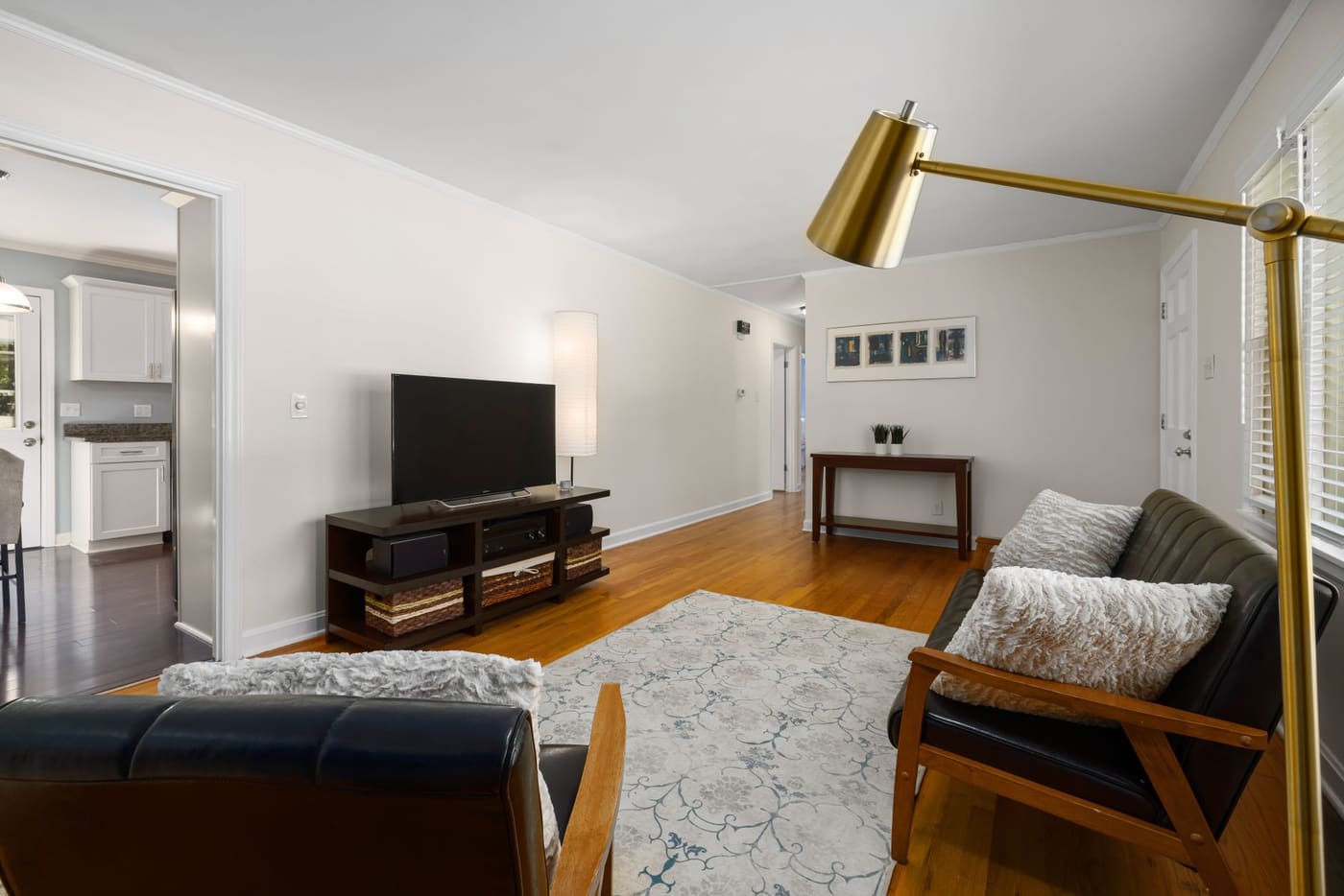 A living room corner with a tall brass floor lamp, a patterned rug and a wooden armchair