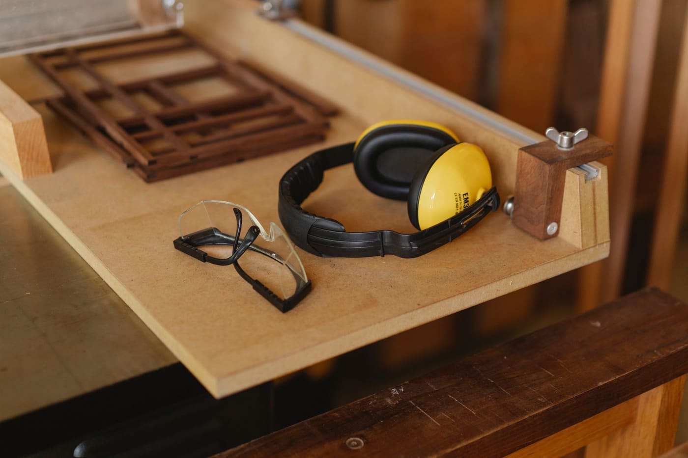 Safety glasses and yellow ear defenders resting on a workshop bench
